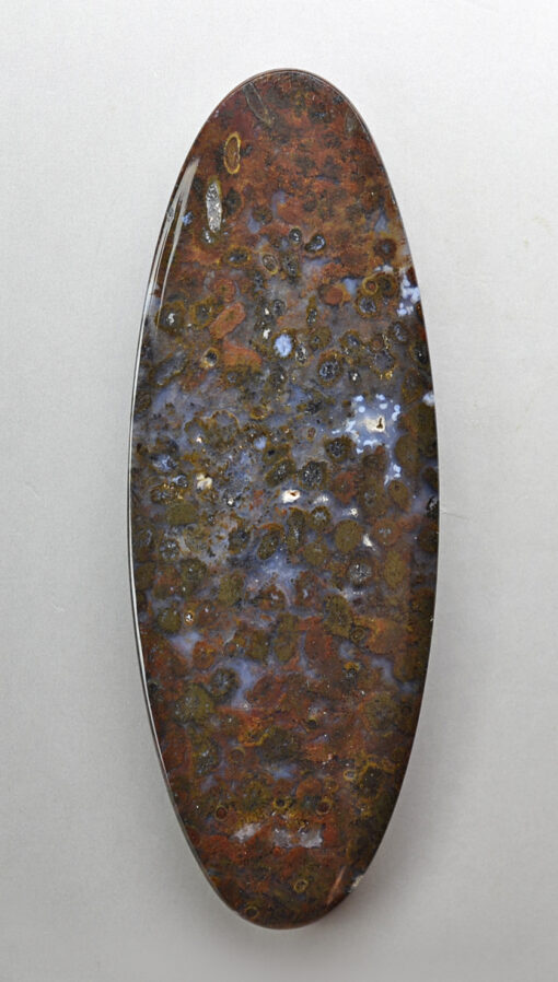 An oval shaped stone with brown and blue spots on it.