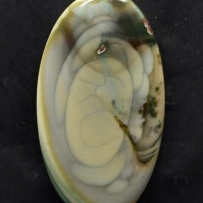 A white and green agate pendant on a black surface.