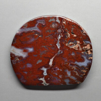 A piece of red and white agate on a white surface.