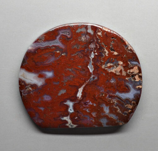 A piece of red and white agate on a white surface.