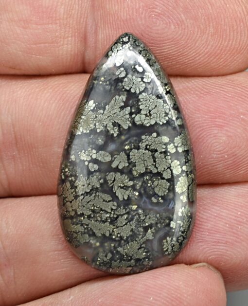 A person is holding a black and gray stone in their hand.