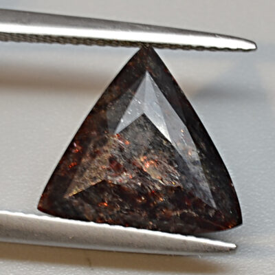 A brown diamond is being cut with a pair of pliers.