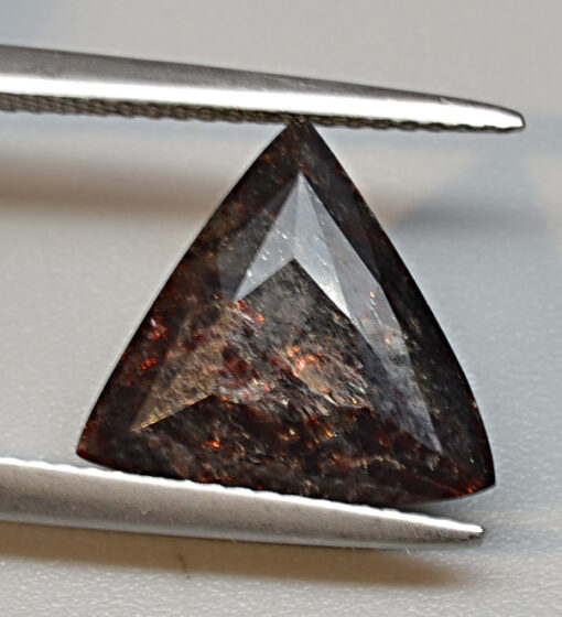 A brown diamond is being cut with a pair of pliers.