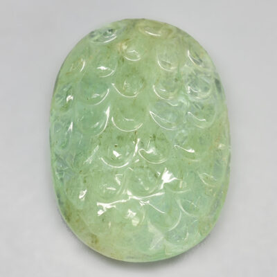 A green jade cabochon on a white surface.