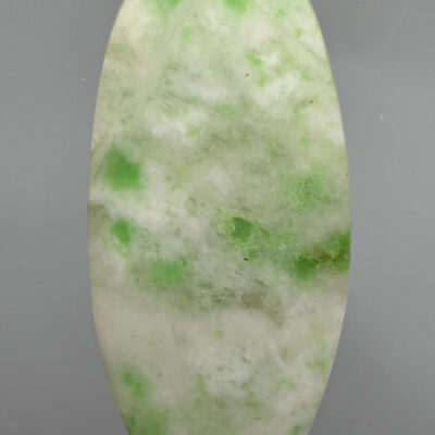 A green and white jade stone on a gray background.