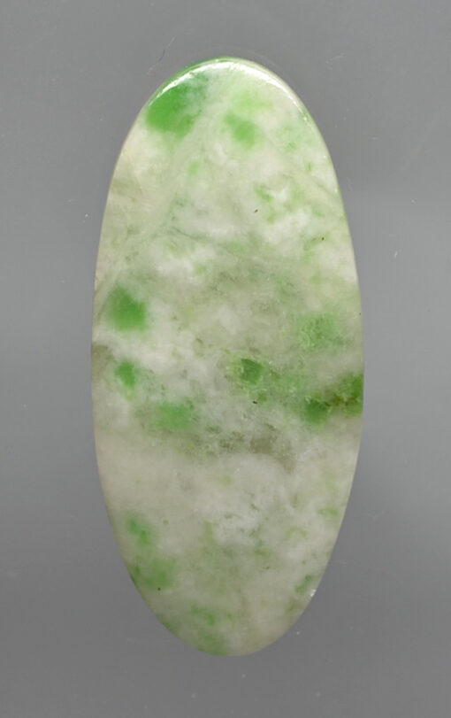 A green and white jade stone on a gray background.