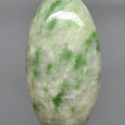 A green jade stone on a gray background.