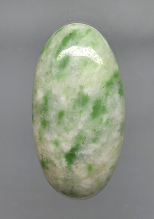 A green jade stone on a gray background.