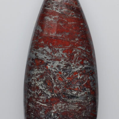 A red and gray stone pendant on a white surface.