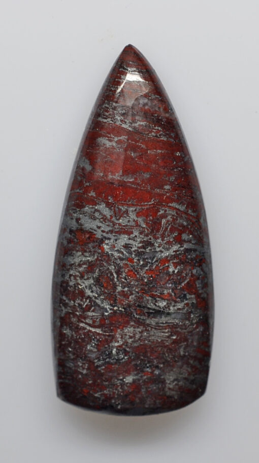 A red and gray stone pendant on a white surface.