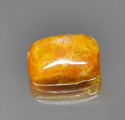 A piece of yellow amber on a grey surface.