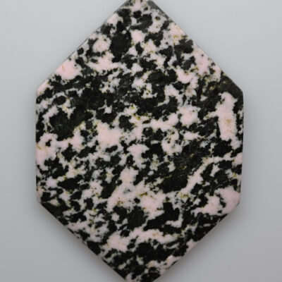 A hexagonal piece of pink and black granite.