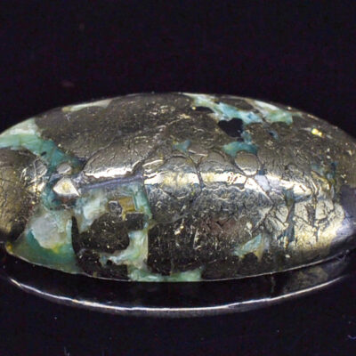 An oval shaped turquoise stone on a black surface.