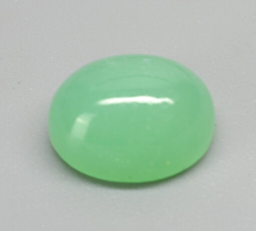 A green jade stone on a white surface.