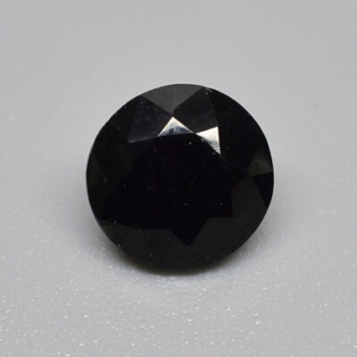 A round black diamond on a white surface.
