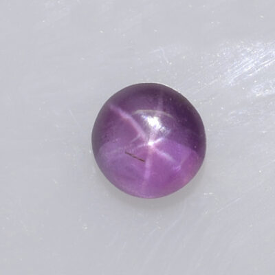 A purple star sapphire on a white surface.