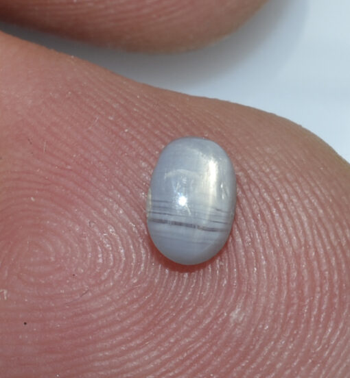 A person's finger with a small grey stone on it.