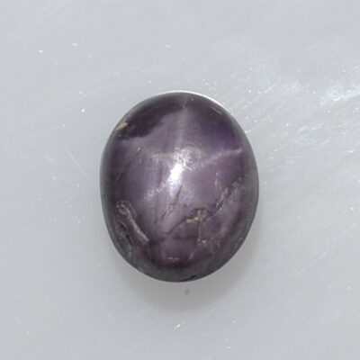 A purple amethyst stone on a white surface.