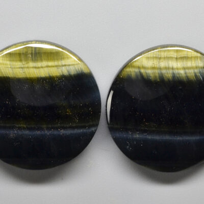 Two oval tiger's eye cabochons on a white surface.