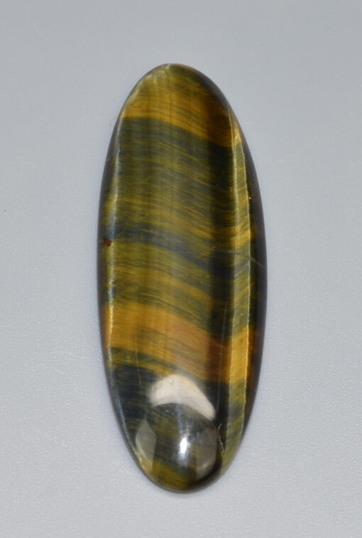 An oval tiger eye stone on a white surface.