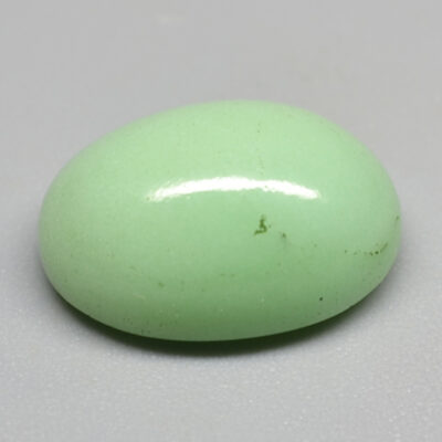 An oval green jade stone on a white surface.