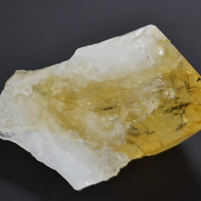 A piece of yellow quartz on a black surface.