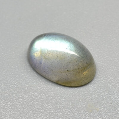 An oval shaped labradorite on a white surface.