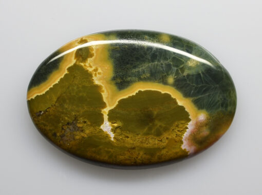 A green and yellow agate on a white surface.