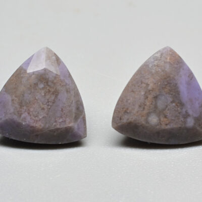 A pair of purple apatite stud earrings on a white surface.