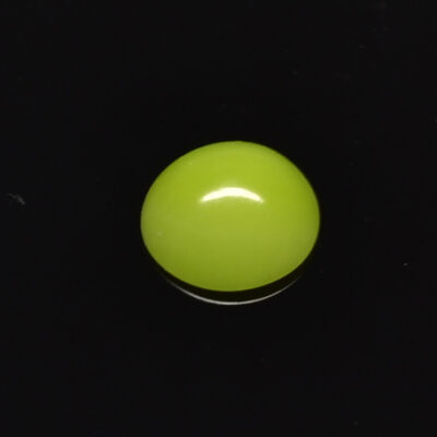 A lime colored stone on a black surface.