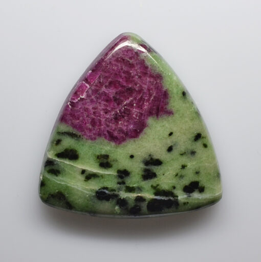 A green and pink stone pendant on a white surface.