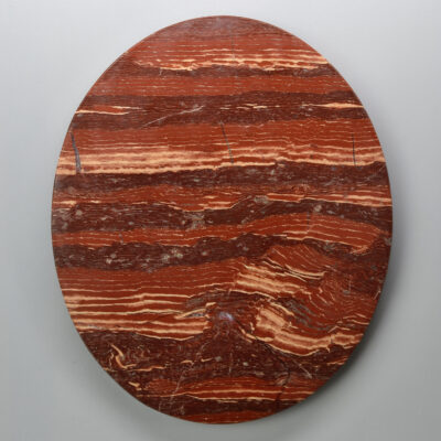 A circular piece of red marble on a white background.