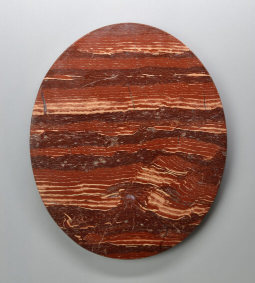 A circular piece of red marble on a white background.