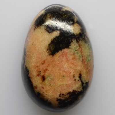 A stone with black and green spots on it.