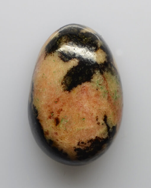 A stone with black and green spots on it.