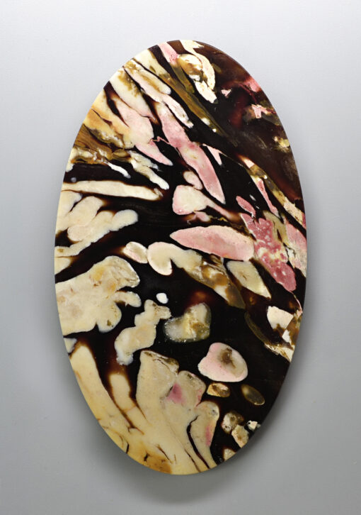 An oval shaped piece of art with black and pink paint on it.