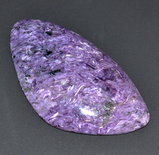 A purple jade stone is being held in a person's hand.