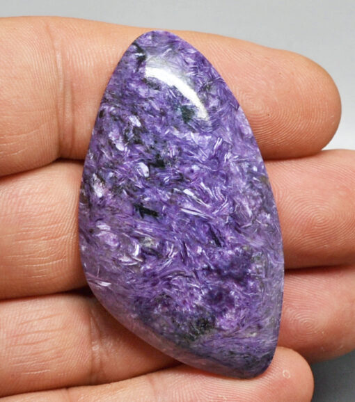 A purple jade stone is being held in a person's hand.