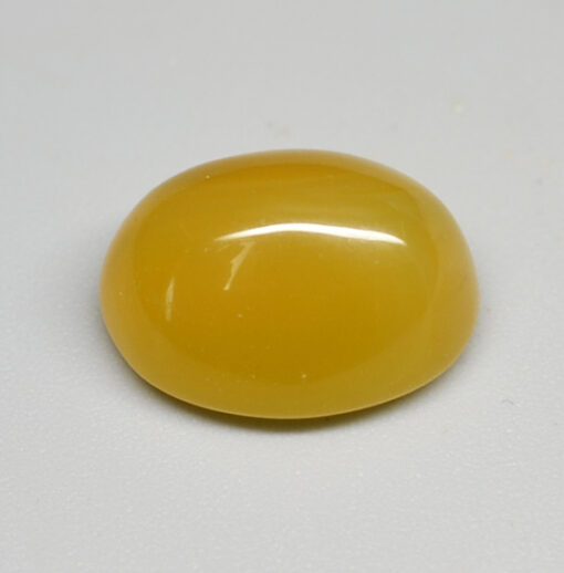 A yellow oval cabochon on a white surface.