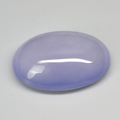 An oval shaped purple jade stone on a white surface.