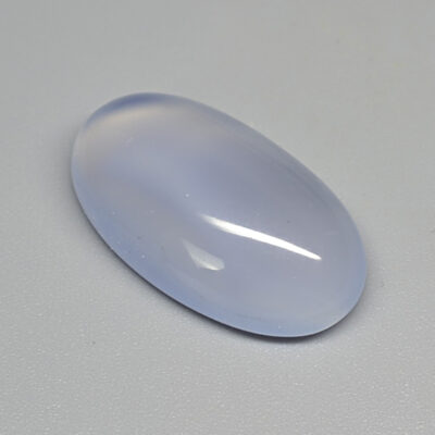 An oval shaped blue opal stone on a white surface.