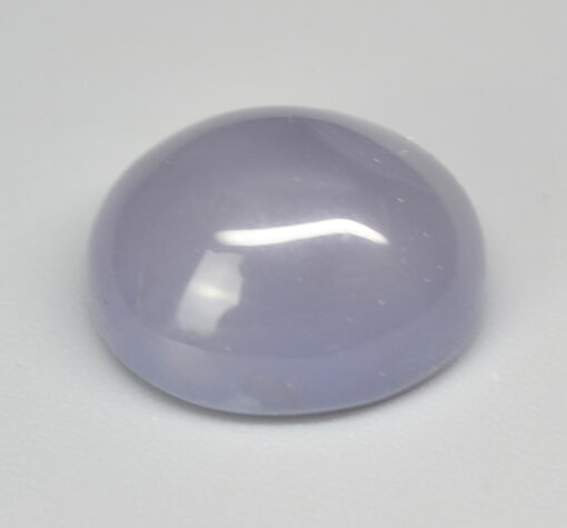 A round purple jade stone on a white surface.