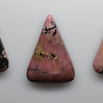 Three pink and black stone pendants on a white surface.