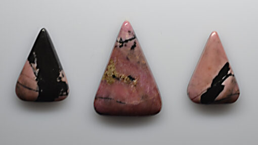 Three pink and black stone pendants on a white surface.