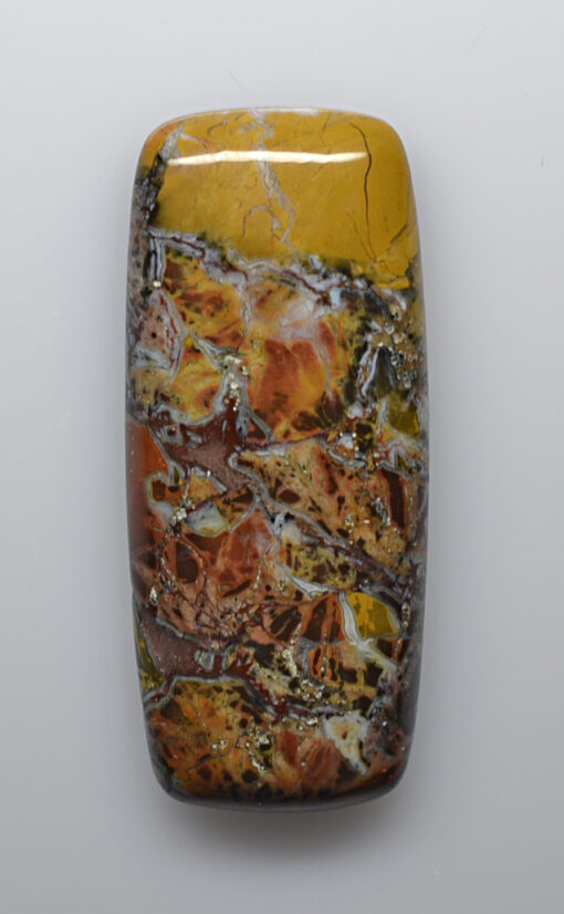 A yellow and brown piece of jasper on a white surface.