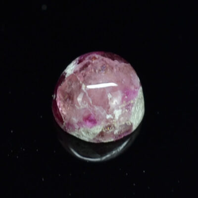A pink sapphire on a black surface.