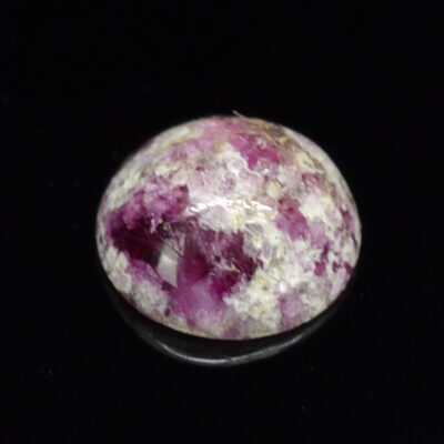 A pink and white stone on a black surface.