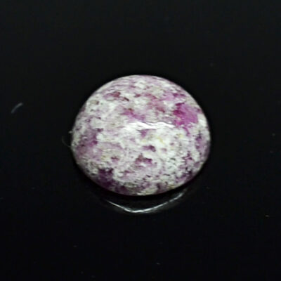 A pink and white stone on a black surface.