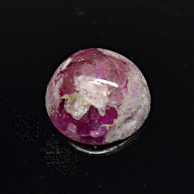 A pink stone on a black surface.