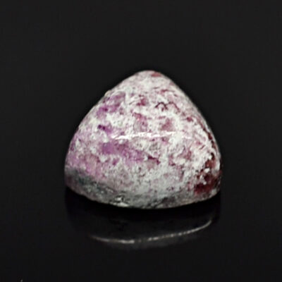 A pink and purple gemstone on a black surface.